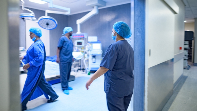 Hospital staff in surgical scrubs walking inside an operating room corridor