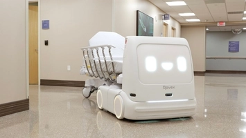 Rovex Rovi robot navigating a hospital hallway alongside a hospital bed